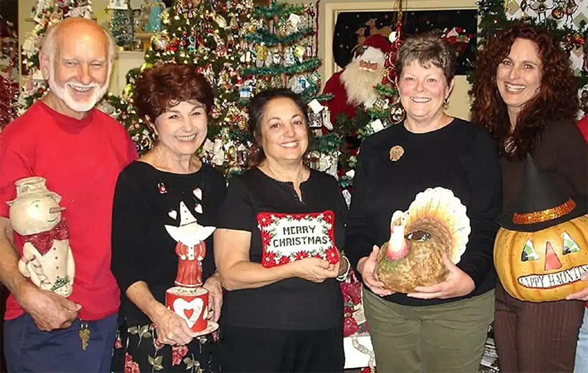 A group of people posing with holiday decorations and festive items at Christmas time.