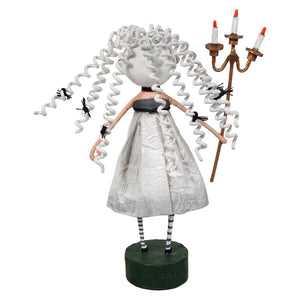 White curly-haired lori mitchell figurine in silver dress holding a three-candle candelabra guiding light halloween decor
