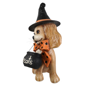 A tan resin halloween frankie witch dog figurine wearing a black glittery hat holding a treat cauldron with an orange bow
