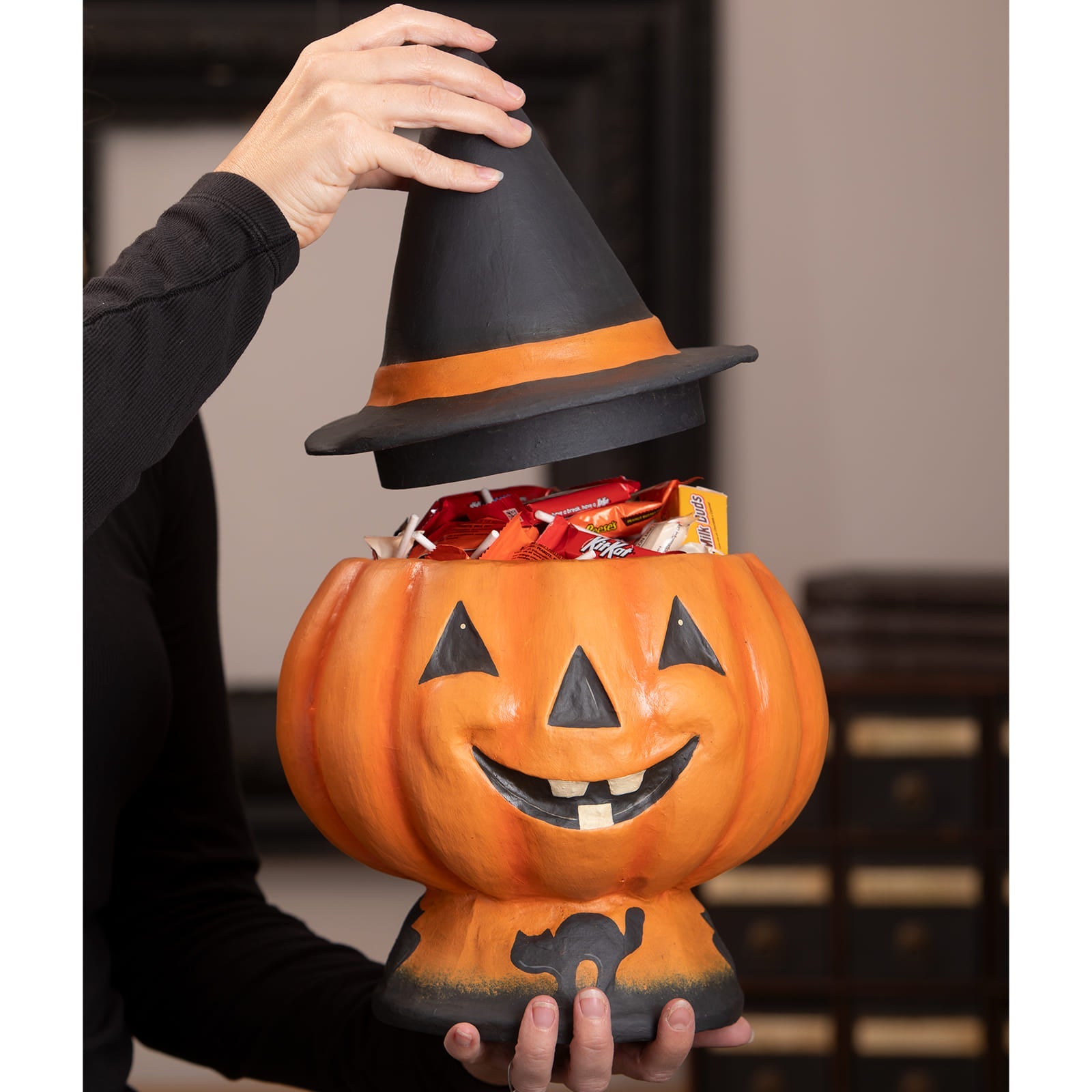 Orange pumpkin-shaped halloween jack o lantern candy bucket with black witch hat lid and black cat silhouette base