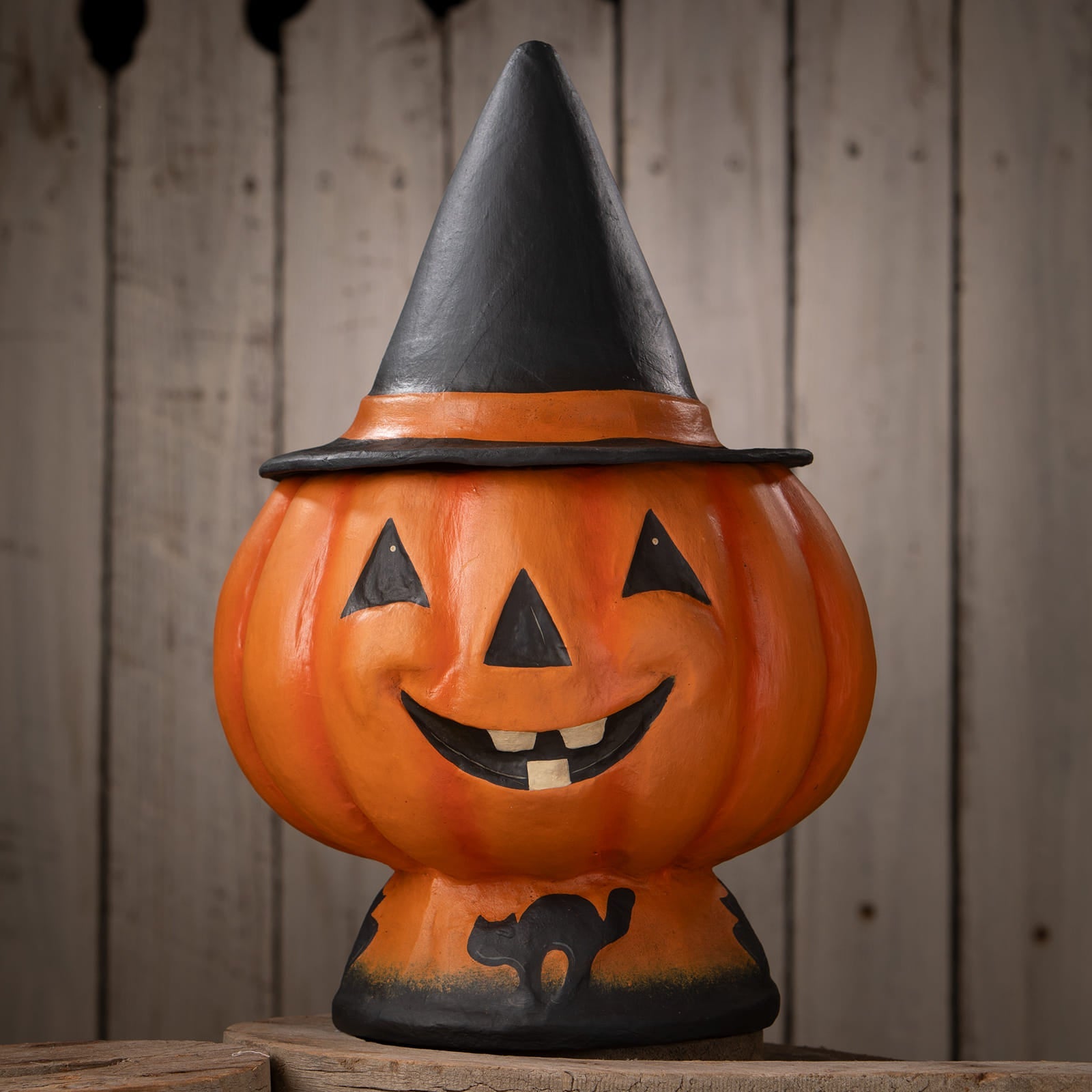 Orange halloween jack o lantern pumpkin decoration with black witch hat smiling face and cat silhouette at base