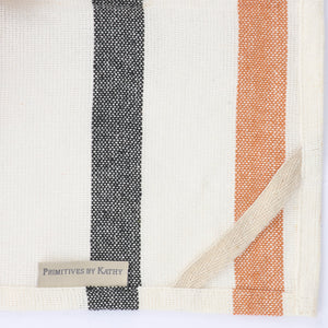 A woven cotton halloween stripe kitchen towel with bold black terracotta orange and cream stripes for breakfast inn kitchen use
