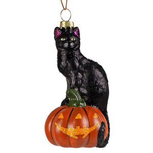 Black glass cat ornament with purple ears and gold glitter sitting on a vintage halloween pumpkin halloween pumpkin ornament