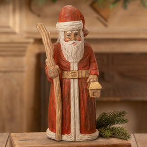 Hand carved santa figurine with red coat white beard holding staff and lantern perfect for folk art santas collection