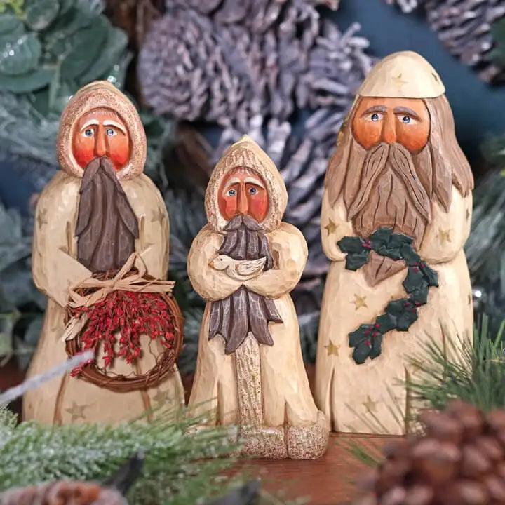 Three wooden nativity figures with winter clothing against a Christmas tree background.