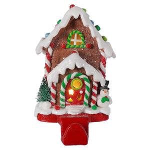 Hand-crafted led lighted gingerbread candy house with glittery brown facade white icing candy cane pillars and glowing window