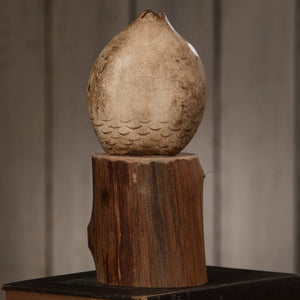 A weathered beige ceramic handcarved 9 inch hoot owl with scalloped pattern on rustic wooden pedestal by bethany lowe design