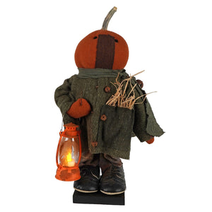 Handcrafted large standing fall colors scarecrow with orange pumpkin head wearing green wool coat holding orange lantern