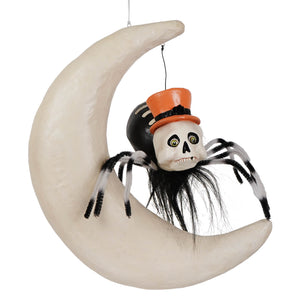A whimsical halloween spider on moon decoration with black and white pipe cleaner legs and an orange glitter hat