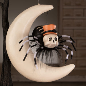 Halloween hanging ornament featuring a black and white pipe cleaner spider on moon with orange top hat on a cream crescent