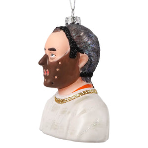 Glass christmas ornament of hannibal lecter bust with glittery black hair brown mask and gold trimmed white garment by cody foster