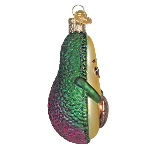 A cute glass avocado ornament with textured green peel, purple base, creamy flesh, perfect figural decor or tree topper