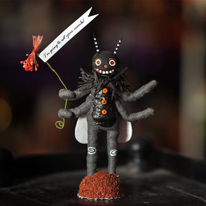 A whimsical black felt happy fly figure with orange button eyes holding a red flower and crumb-eating banner