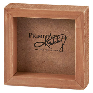 Pink wooden display box with ’Primitives by Kathy Lancaster, Pennsylvania’ text inside.