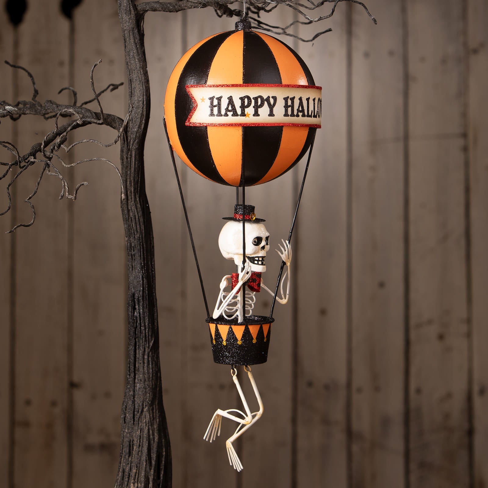Happy halloween balloon with orange and black stripes, skeleton decor figure, glittery accents, and jack o lantern banner
