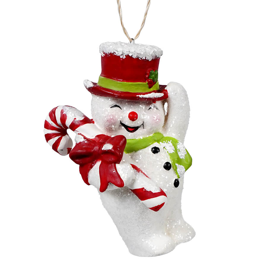 Cheerful snowman ornament wearing a red top hat and green scarf while holding a candy cane.