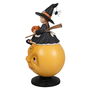Hattie witch on moon halloween witch decor featuring a young witch in black riding a smiling yellow pumpkin head