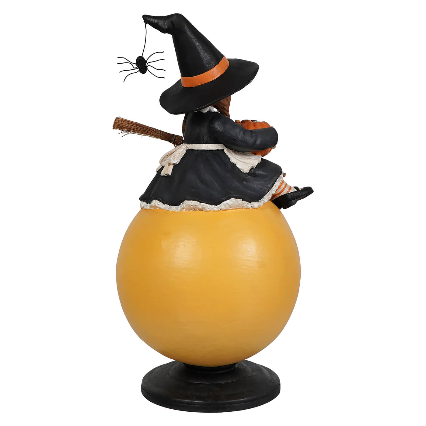 A black witch figurine with an orange hat band and spider sitting on a glossy yellow sphere halloween witches decor