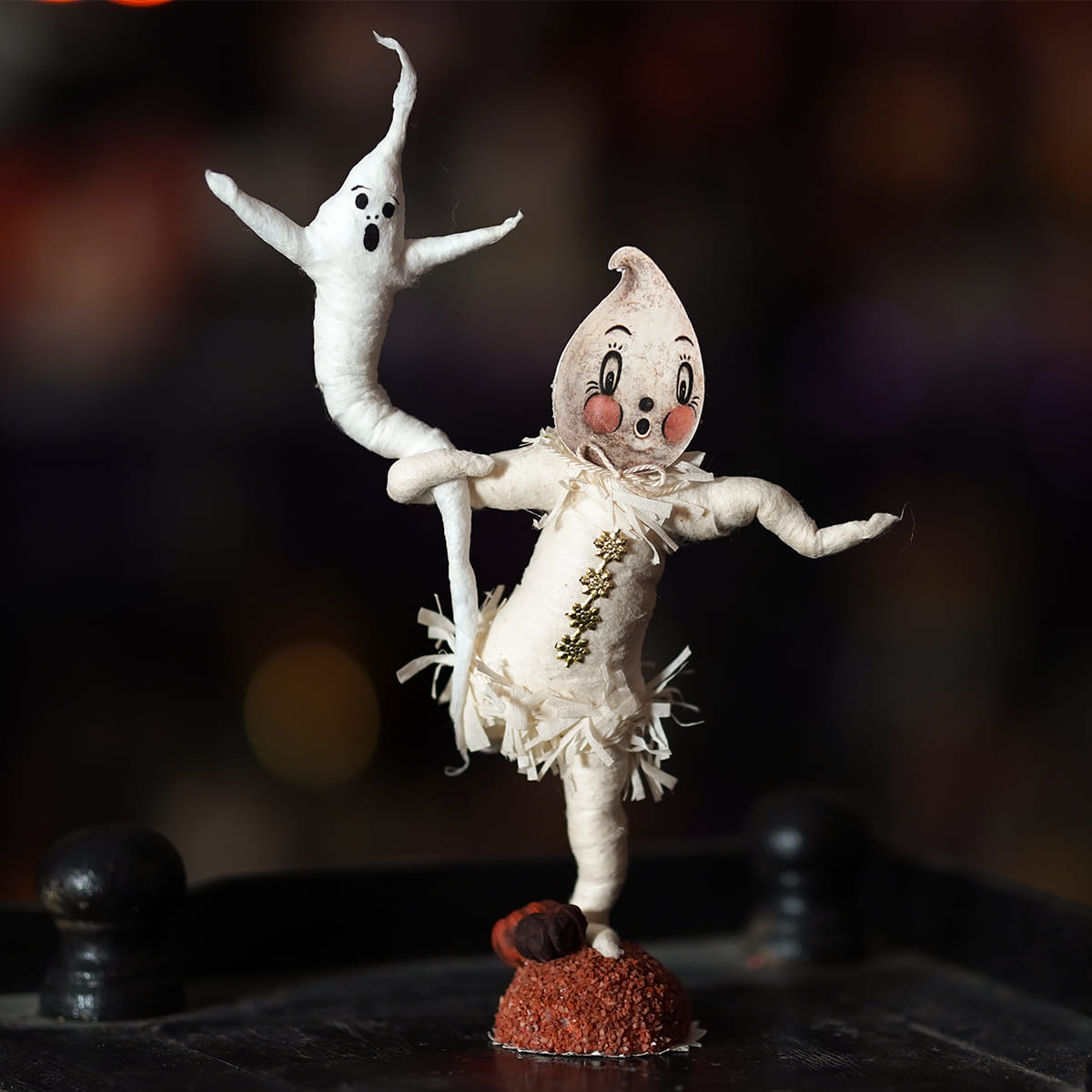 A whimsical white paper-mâché ghost with painted face and frayed lace on red base from johanna parker design haunting ghosts