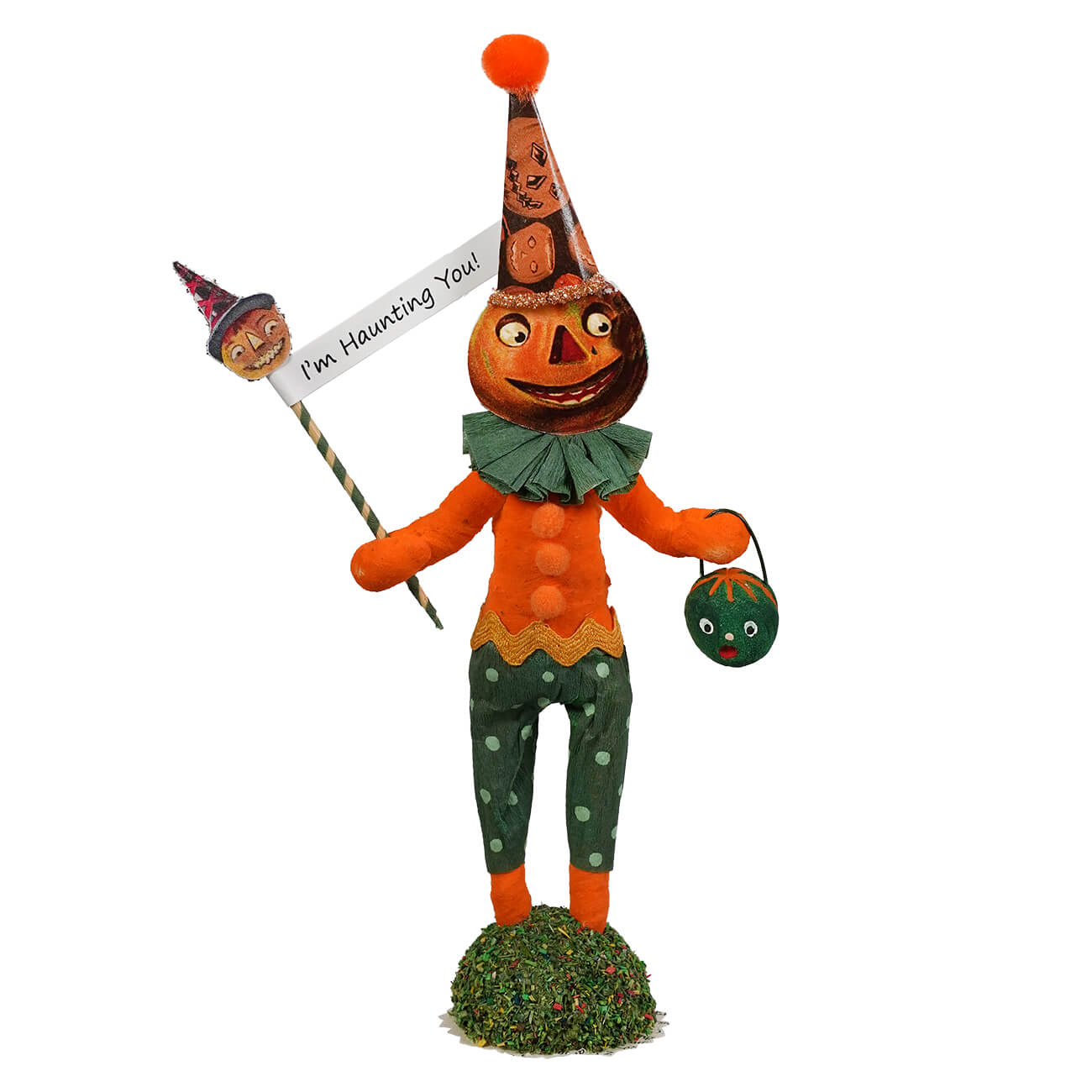 Orange pumpkin-headed scared pumpkin figure handcrafted from paper mache wearing a tall patterned hat holding a sign i’m haunting you