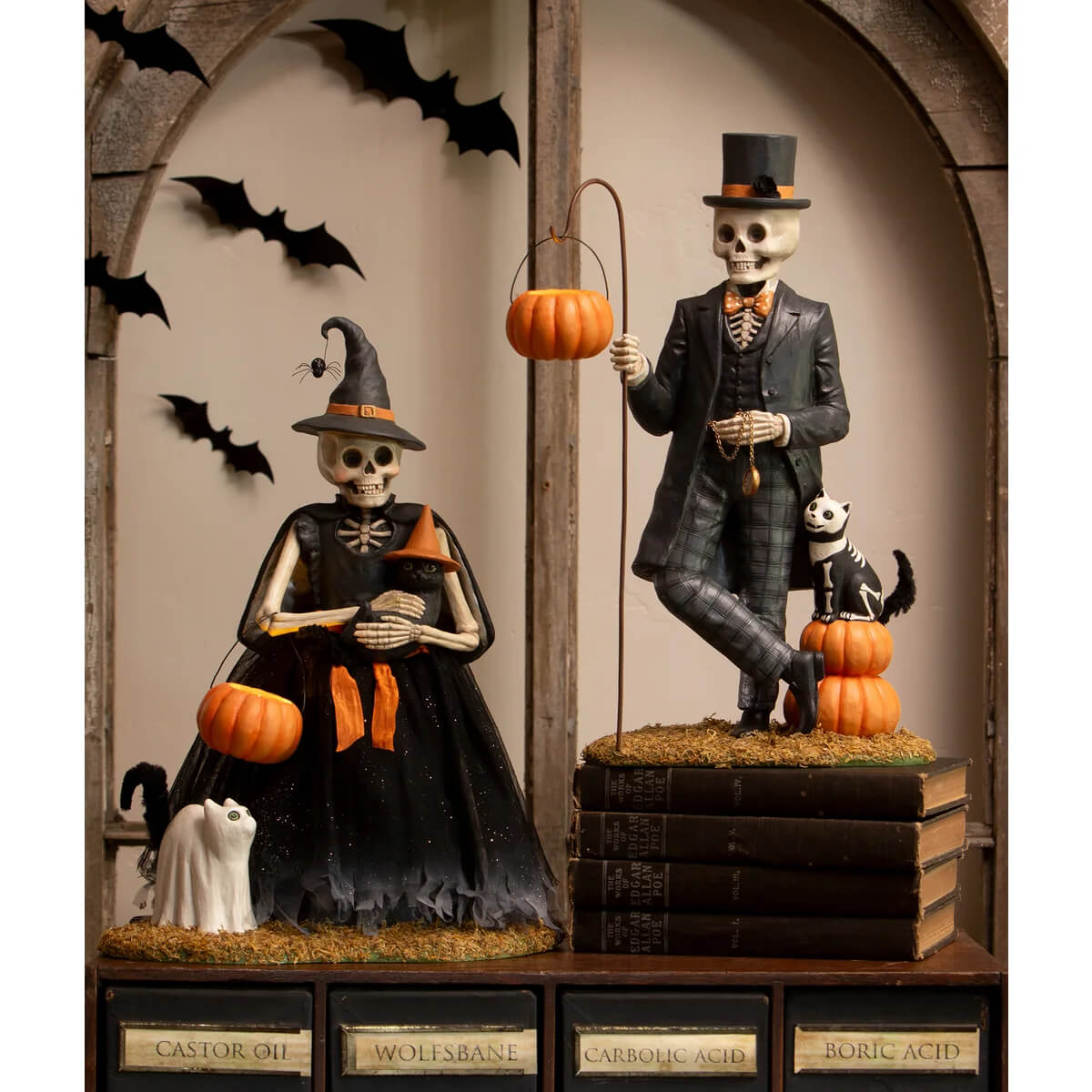 A henry deadison skeleton halloween figurine set featuring a dressed male and female skeleton with orange accents