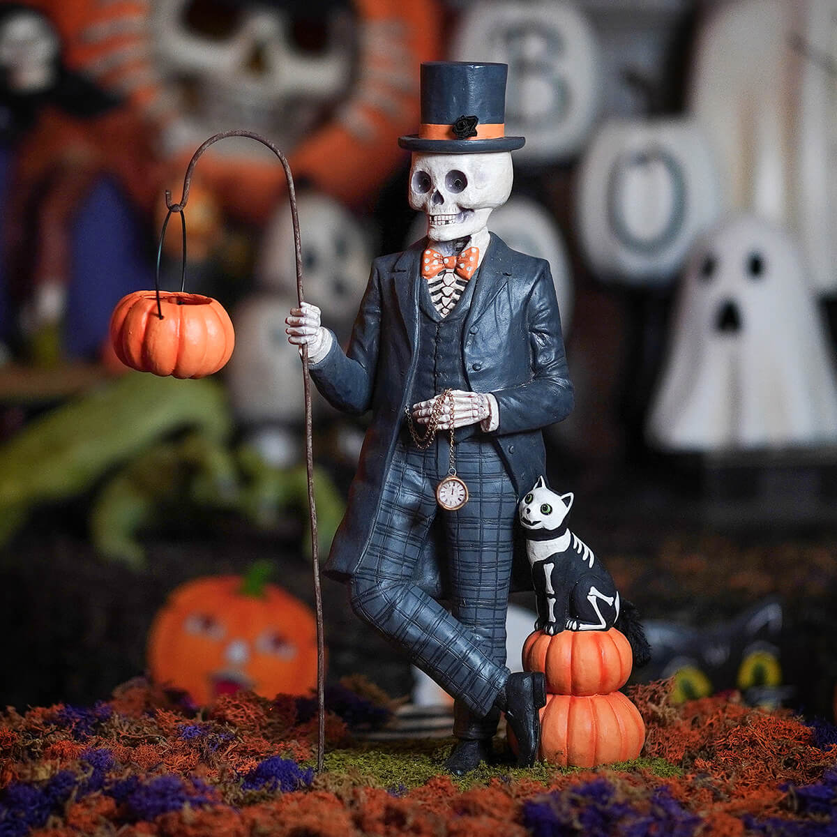 A sophisticated black henry deadison skeleton figurine in a suit and top hat holding a pumpkin lantern on a curved stick