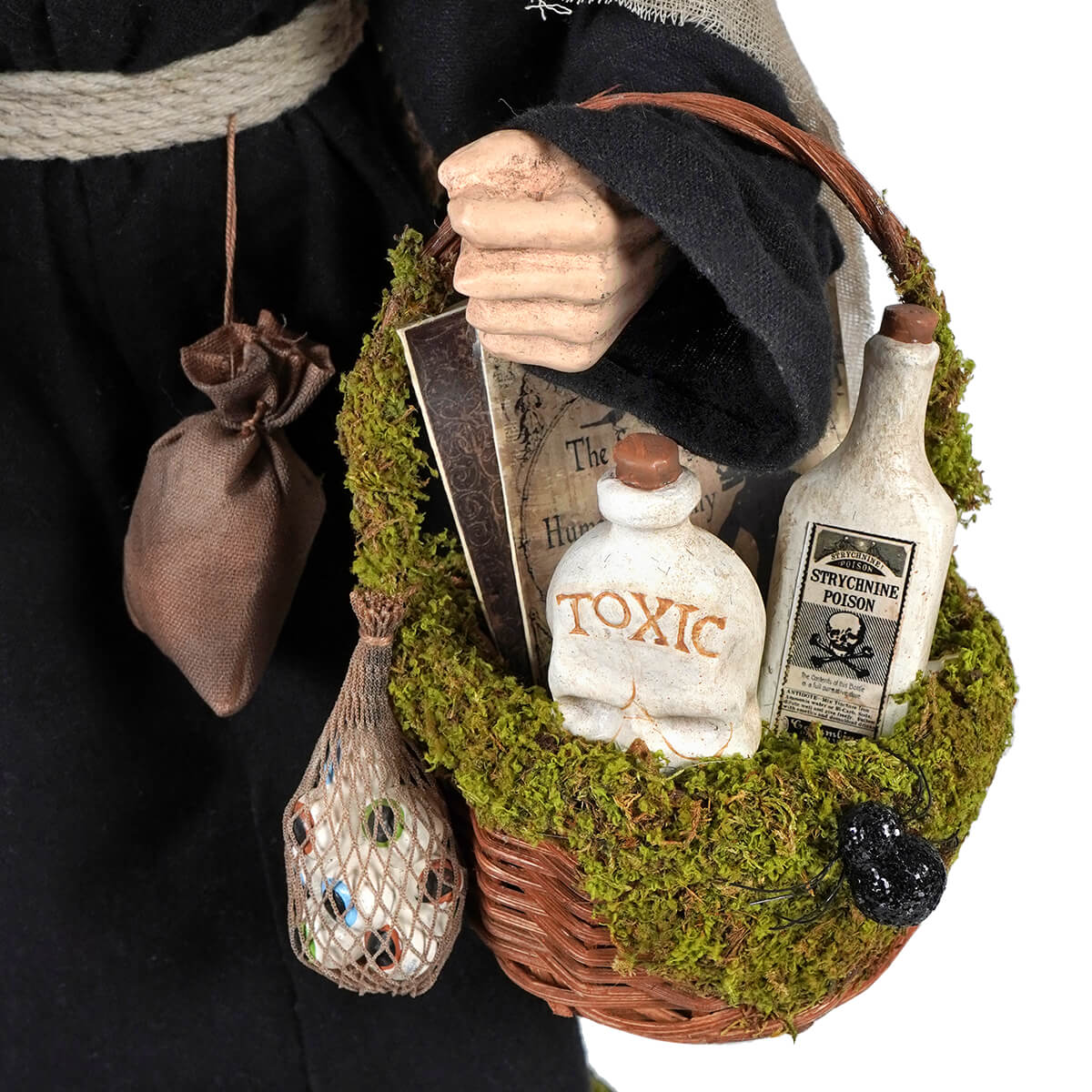 A rustic woven potion basket with green moss holding a white skull bottle labeled toxic and a strychnine poison bottle hildegard