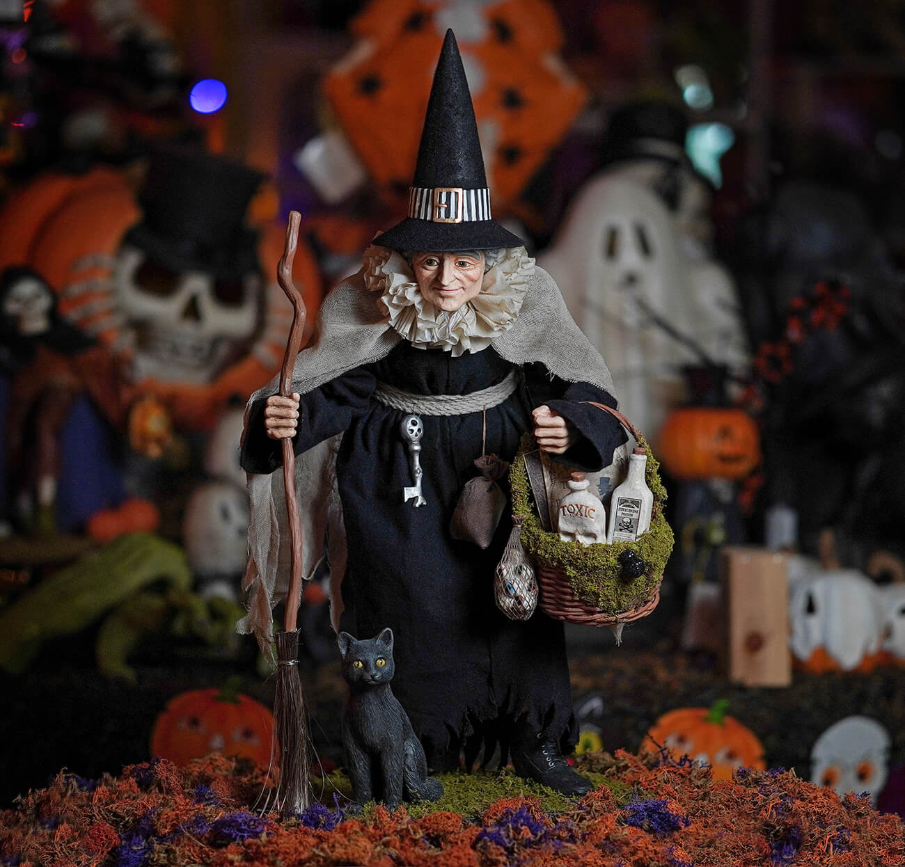 A detailed halloween witch figurine named hildegard wearing a black hat and holding a potion basket with bottles