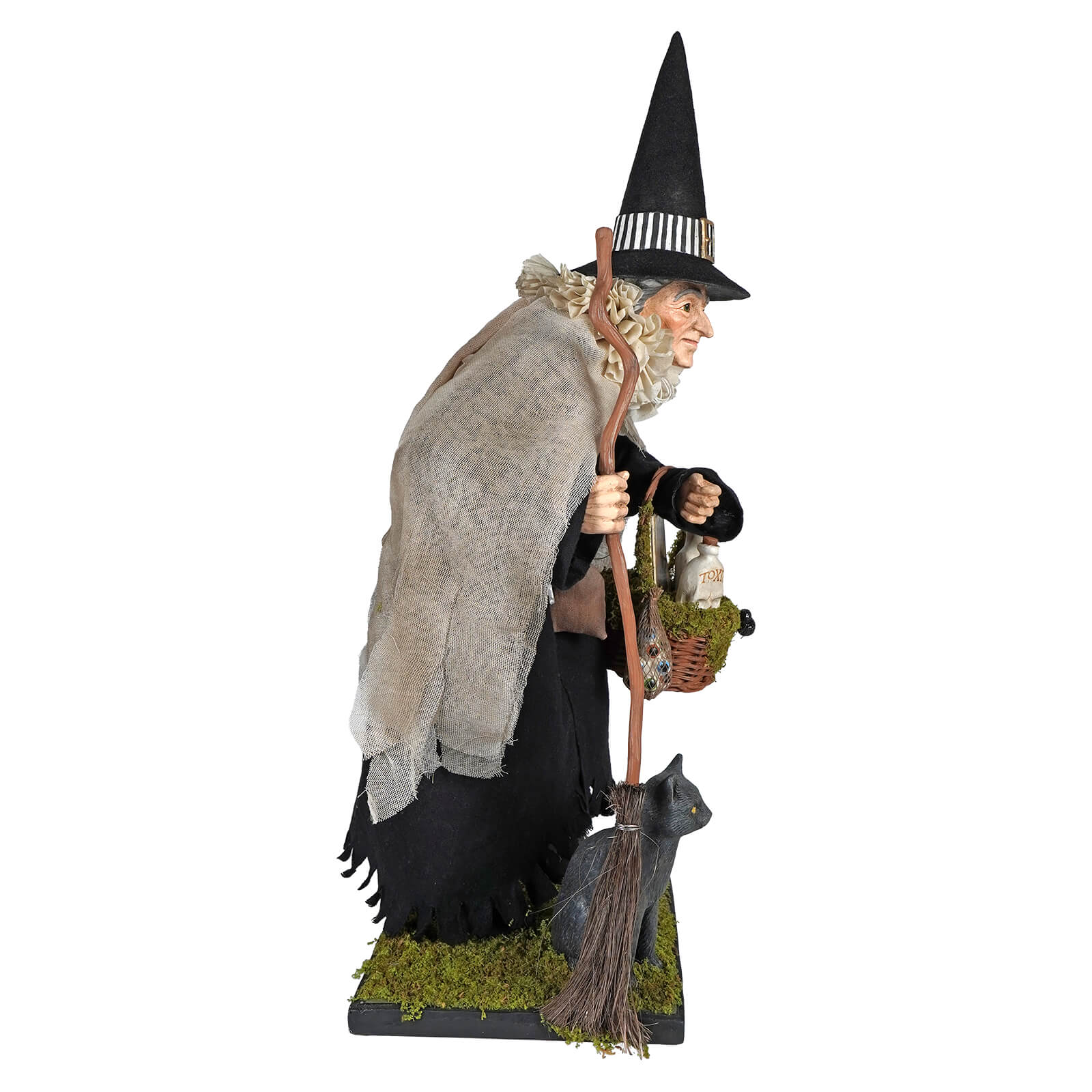 A detailed hildegard witch figurine wearing a black hat and gray shawl holding a broom with a woven potion basket