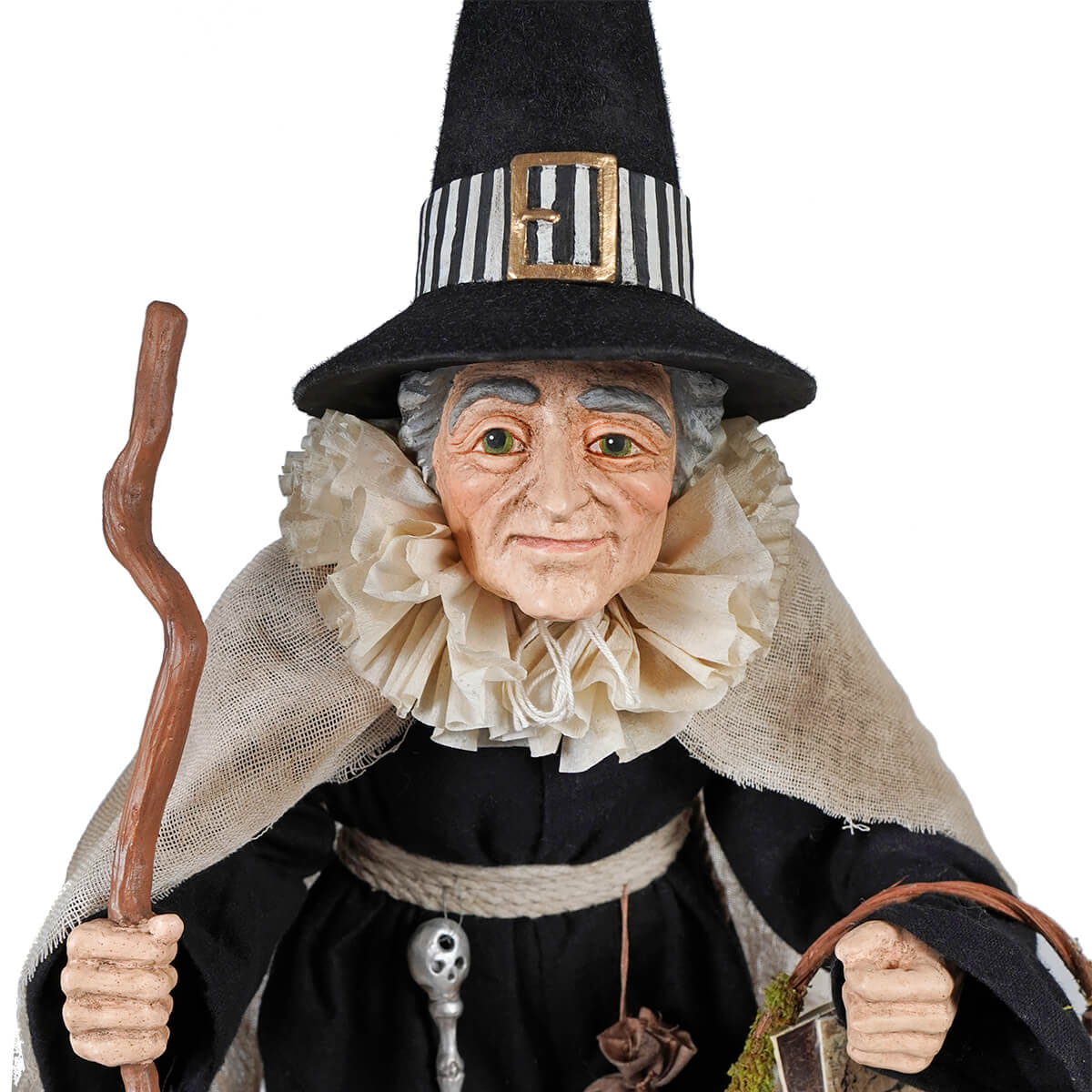 A detailed hildegard figurine of an elderly witch in a black hat with white stripes holding a potion basket