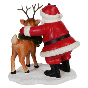 Red and white santa figure hugging a brown reindeer with green garland perfect folk art santas santa with rudolph