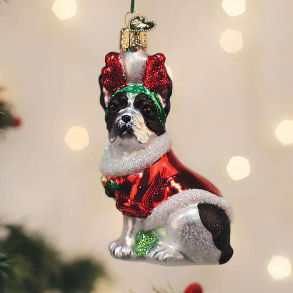 A festive glass french bulldog ornament featuring a black and white dog in a red glittery sweater and green bow tie