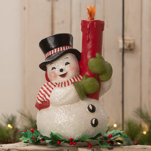 A cheerful white glittery holly berry snowman figurine by bethany lowe designs holding a red candle flame