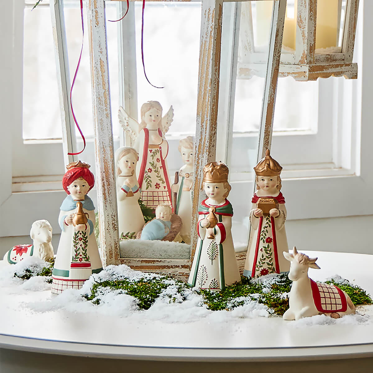 Nativity scene with decorative figurines arranged on a snowy surface.