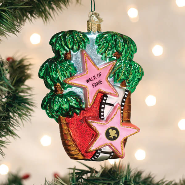 A pink and red glass hollywood walk of fame ornament shaped like a star surrounded by green palm trees perfect for christmas