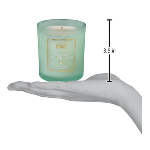 A translucent mint green glass homemade gingerbread candle jar with gold label held in hand by creative co op
