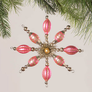 Ornate pink and gold snowflake-shaped Christmas tree ornament.