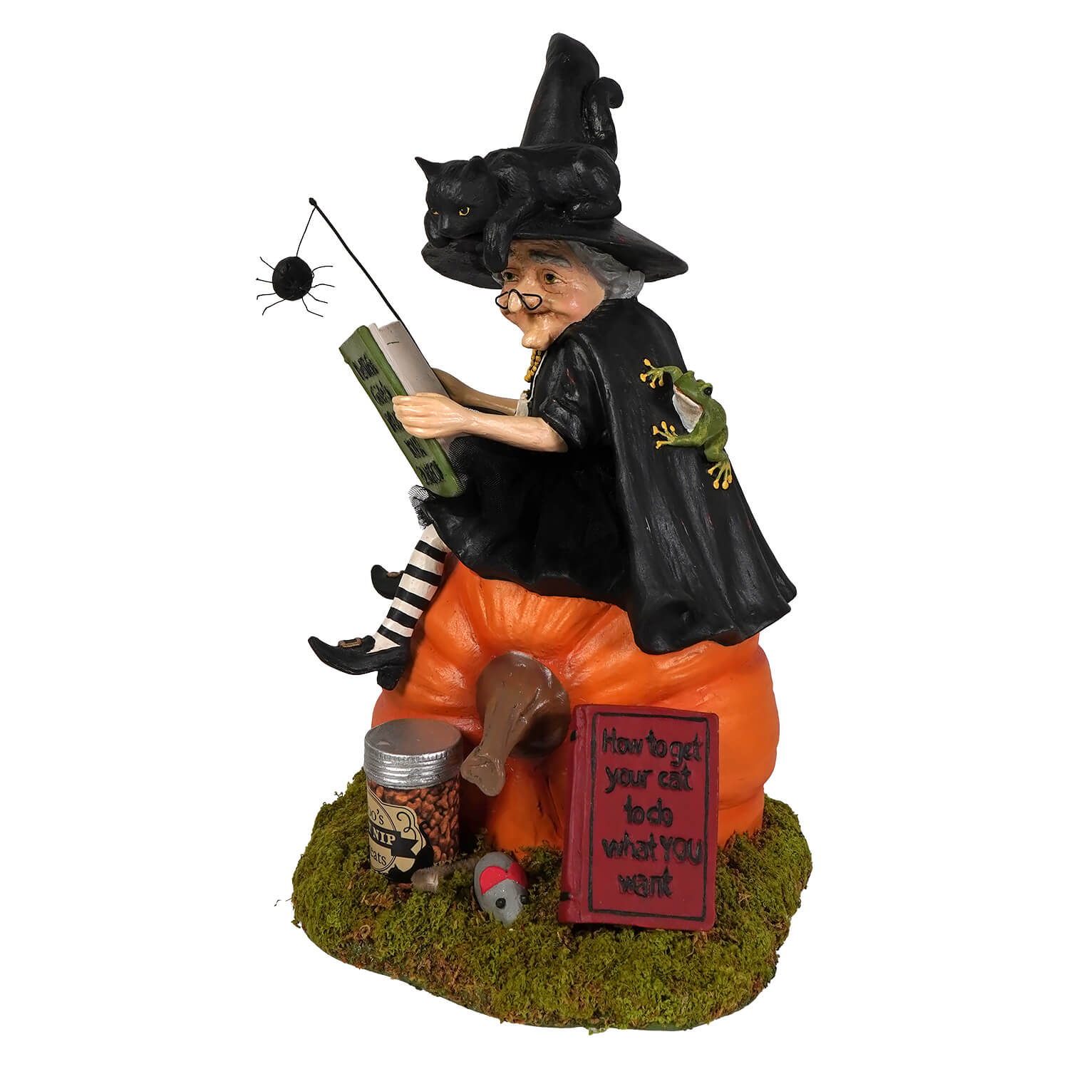 A whimsical bethany lowe halloween witch figurine with black pointed hat reading a book on an orange pumpkin base with black cat theme
