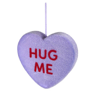 Purple plush heart with ’HUG ME’ written in red letters.