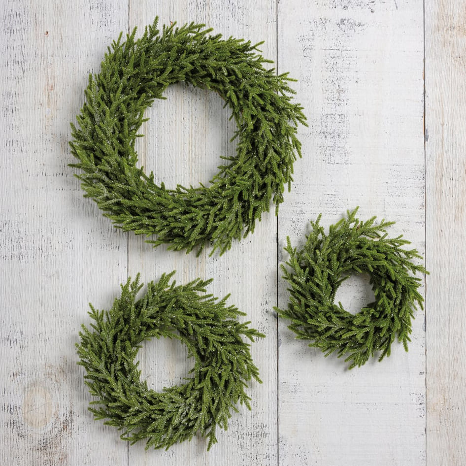 Three frosted green artificial pine ice 14 inch wreaths arranged on white wood perfect for annie schickel christmas wreaths