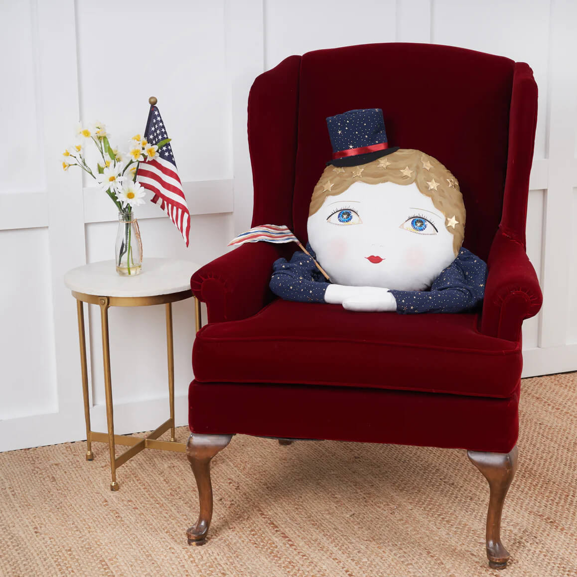 A plush patriotic doll with blonde hair blue eyes and navy glitter top hat on a red velvet chair for indy zombinaland decorative pillows by tracy scheff