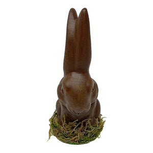 A glossy ino schaller brown sitting easter bunny figurine made of german paper mache with red gemstone eyes on green moss