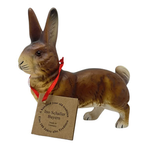 A brown ino schaller paper mache walking easter bunny with detailed fur and a red ribbon around its neck