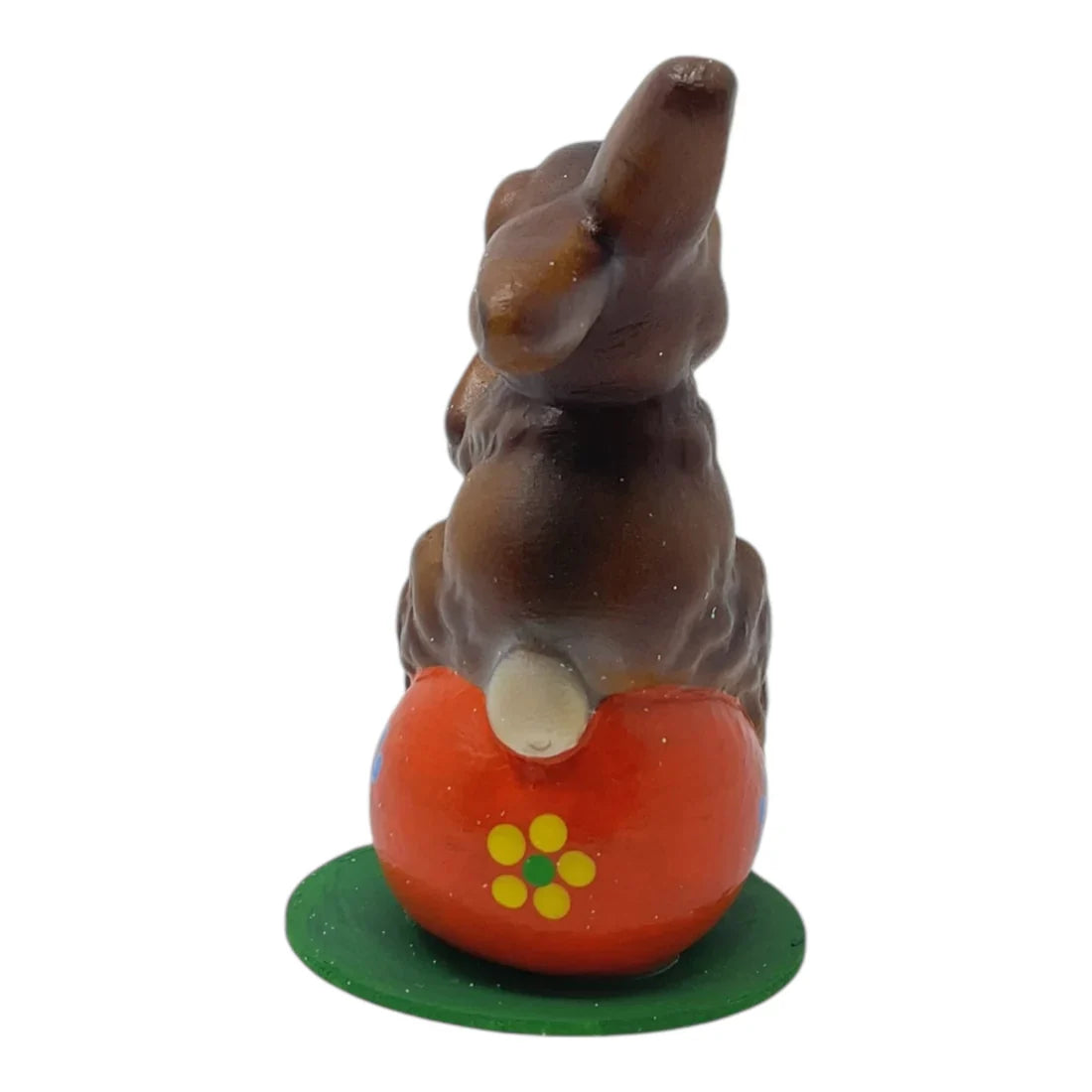 A glossy dark brown ino schaller easter chocolate bunny on a bright orange german paper mache pumpkin base