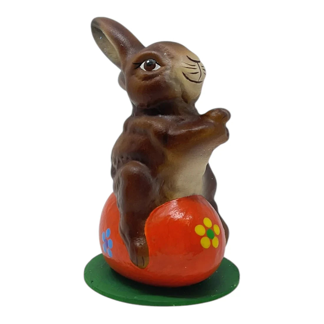 Ino schaller easter brown ceramic bunny sitting on vibrant orange egg with yellow blue floral patterns on green base german paper
