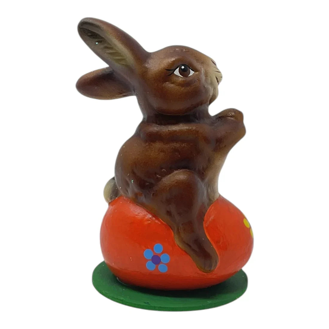 Brown ceramic schaller easter bunny sitting on orange egg with blue flowers on green base german paper mache decor