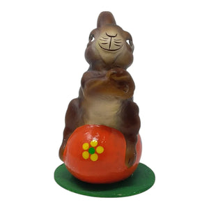 Brown ceramic schaller easter bunny figurine on red egg with floral design on green base german paper mache