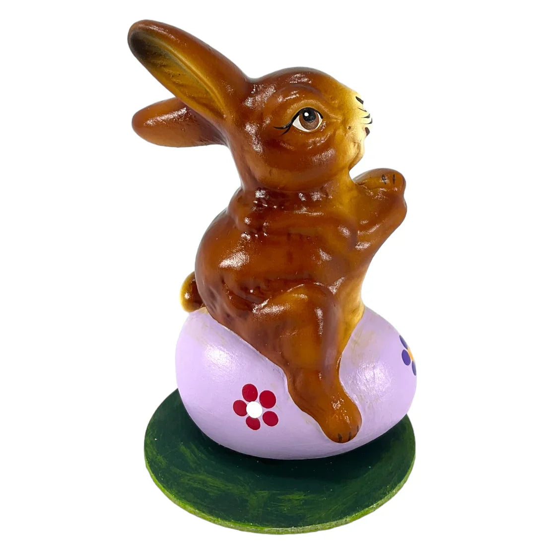 A glossy brown ceramic ino schaller easter bunny on a purple egg with red flowers on a green german paper base