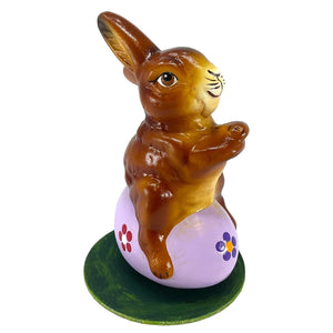A glossy brown ino schaller easter bunny ceramic figurine sitting on a purple floral german paper mache egg base