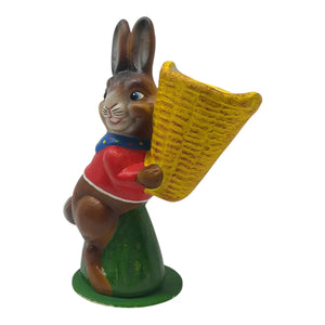 A charming ino schaller easter brown rabbit figurine in red sweater holding a yellow basket made of german paper mache